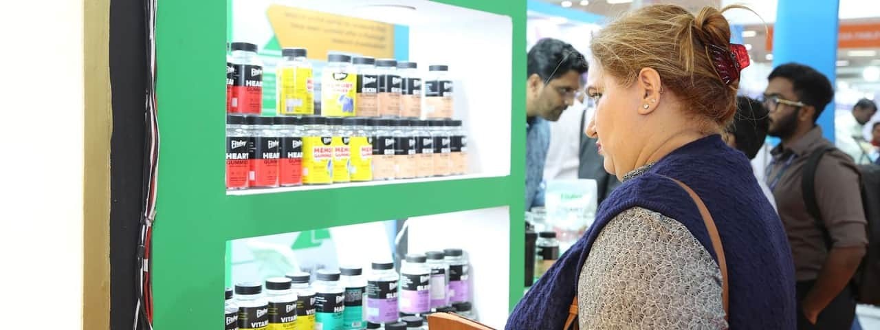 An attendee observes a shelf displaying numerous products at the Vitafood India event.