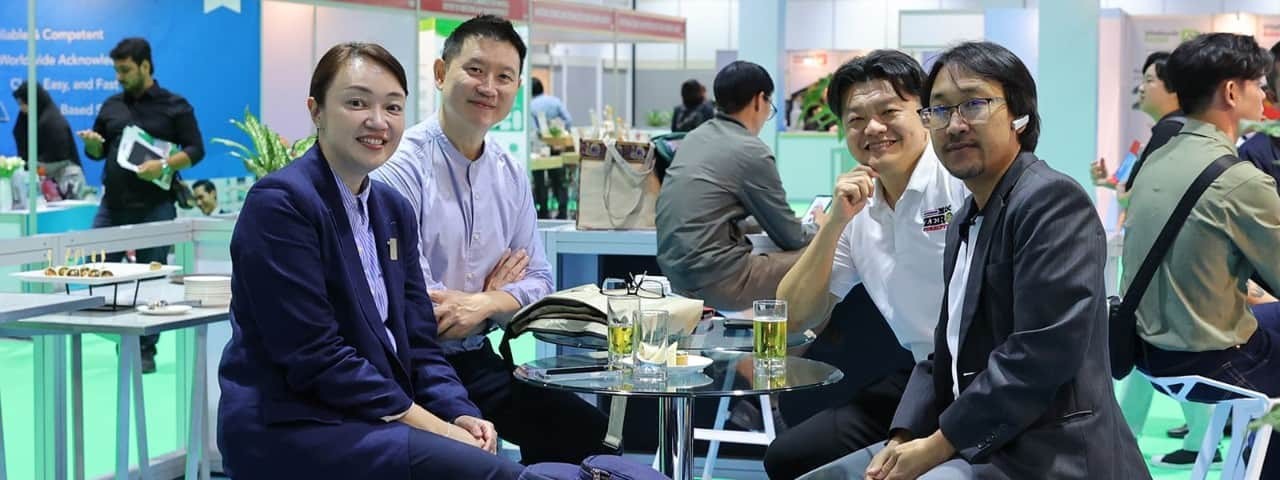 At the Vitafood Asia event, attendees seated around a high table smile at the camera.